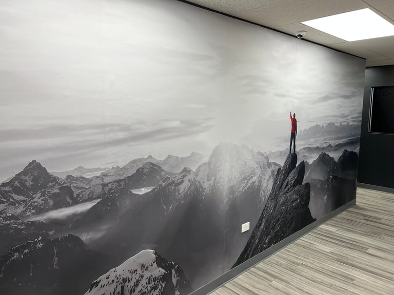 Large mural of a figure standing on a mountain peak overlooking a vast misty valley landscape