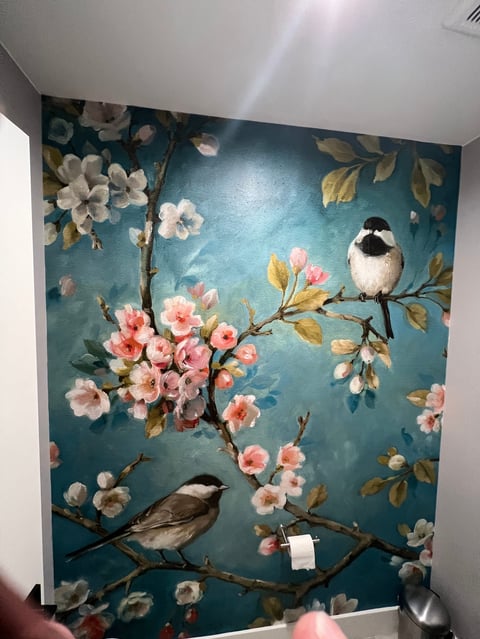 Wall mural featuring a teal background with flowering branches and two small birds perched on branches adorned with pink and white blossoms