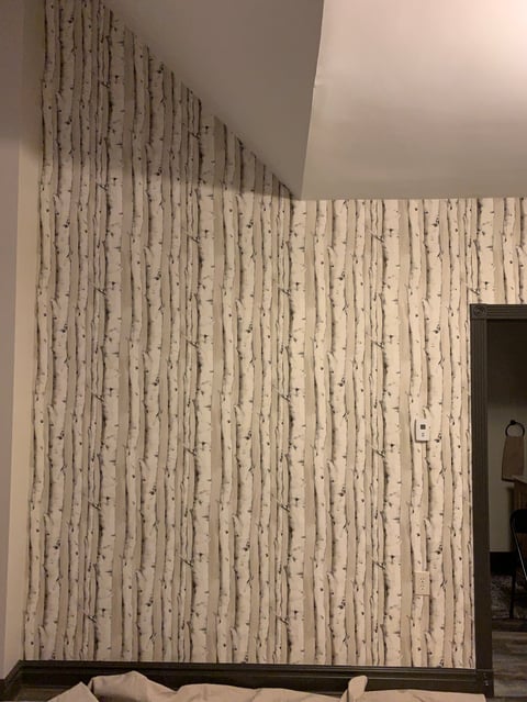 Cream-colored curtains with small dark leaf pattern hanging on interior wall of modern room