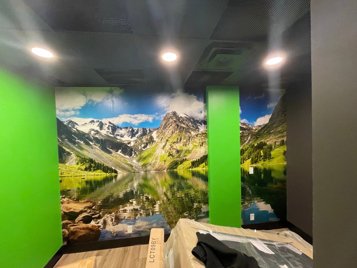 Modern retail interior with bright green walls displaying large mountain lake landscape photography with snow-capped peaks reflected in water