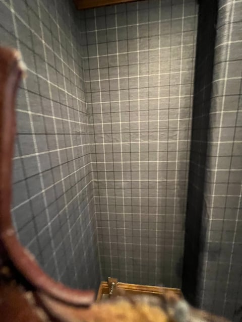 Narrow shower enclosure with small white tile walls and a brass-colored showerhead fixture mounted at the bottom
