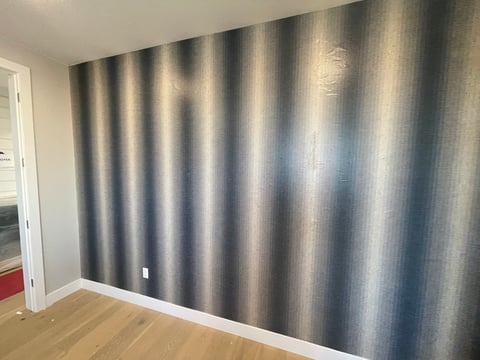 Gray vertical striped curtains covering a wall in a modern room with wooden floor and white doorway