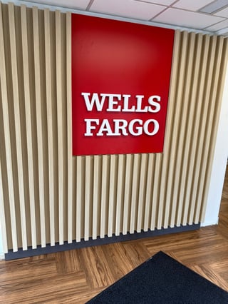 Wells Fargo red logo sign on beige vertical panels with wooden flooring