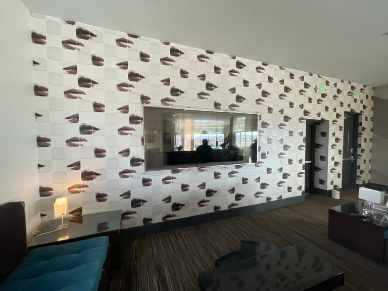 Modern office space with decorative wall featuring repeated brown geometric patterns, large mounted monitor, and dark wooden flooring