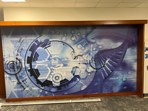 Large digital display screen showing abstract blue technology and mechanical design with gears and circuit patterns in a modern indoor space