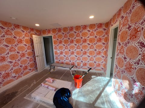 Interior room with red damask patterned wallpaper, two white doors, recessed lighting, and construction materials on the floor