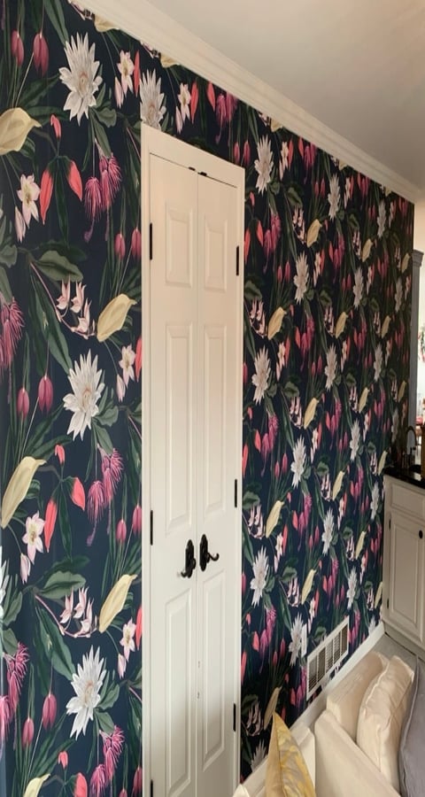 Bedroom wall with dark floral wallpaper featuring white, pink, and yellow flowers, white six-panel closet door in center, beige ceiling