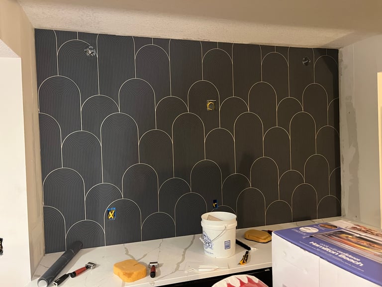 Large black wall mural with gold geometric arch pattern, desk workspace below with supplies and materials