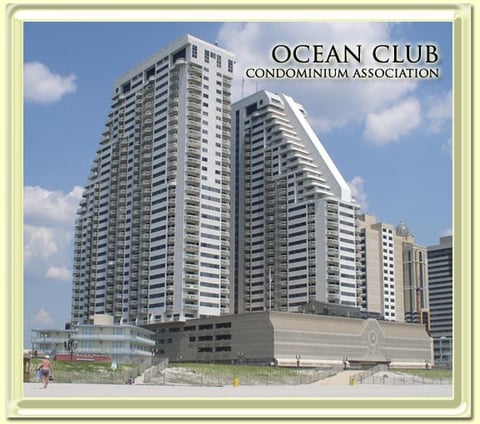 Ocean Club Condominium Association high-rise beachfront building with white and gray curved towers under blue sky