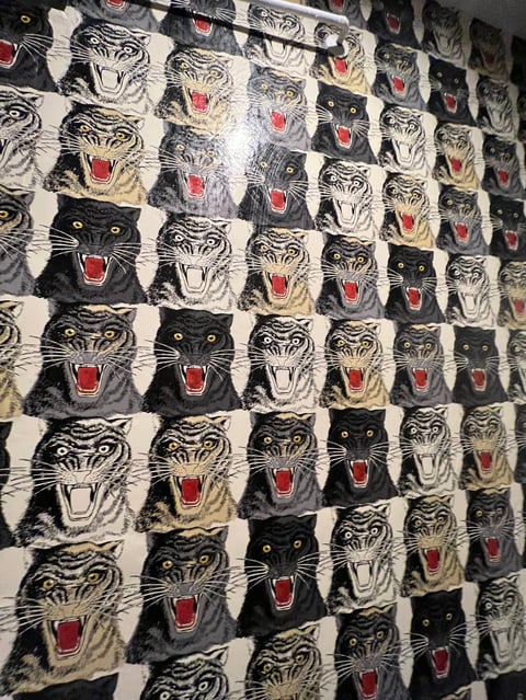 Repeating pattern fabric or wallpaper featuring alternating black and white tiger and panther heads with red open mouths