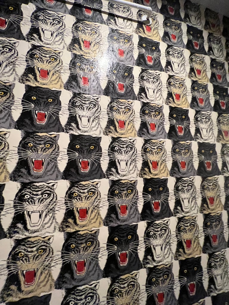 Repeating pattern fabric or wallpaper featuring alternating black and white tiger and panther heads with red open mouths