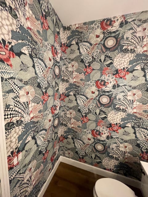Bathroom corner with decorative patterned wallpaper featuring intricate black, red, and beige designs including floral and geometric motifs