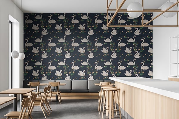 Modern cafe interior with swan-patterned dark wallpaper, wooden dining furniture, white counter, and geometric ceiling fixture