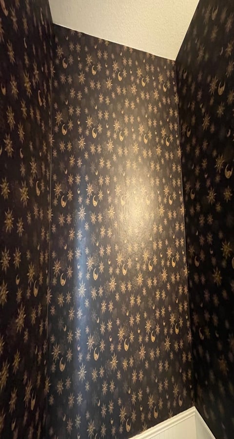 Dark blue wallpaper with gold snowflakes and ornaments pattern covering interior room walls